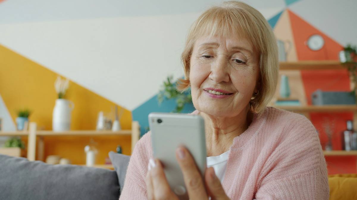 A relaxed adult in their 60s playing a mobile puzzle game on a large-screen smartphone; interface shows clear fonts, high-contrast buttons, and no intrusive ads — gaming for older adults
